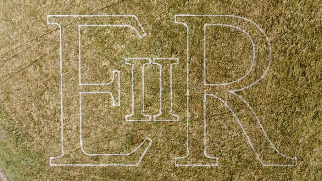 Large ER II lettering outlined in white paint on grass, viewed from above
