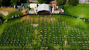 Aerial view of an outdoor concert with socially distanced seating across a large grassy area, enhanced by precise event site marking for optimal organization.